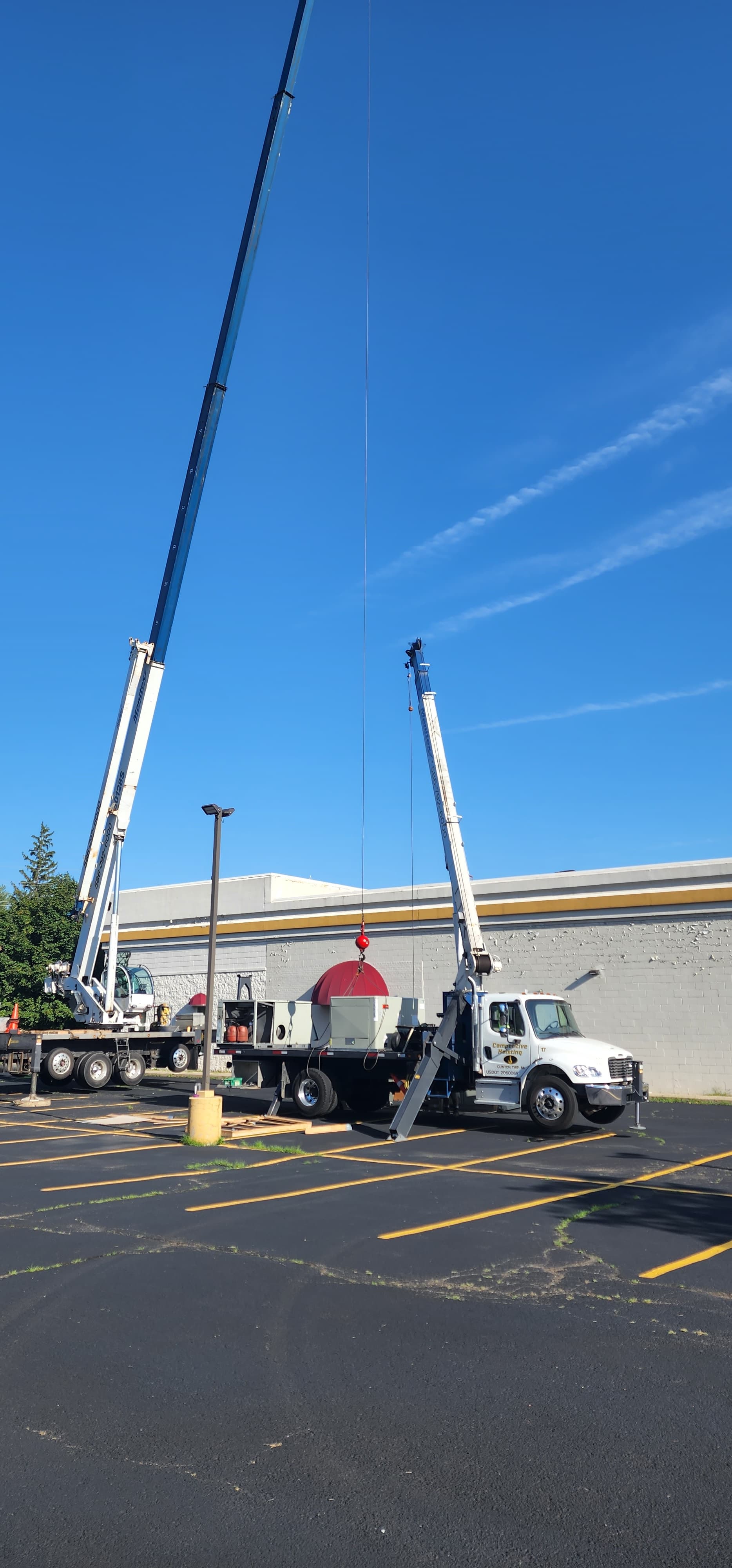 Crane setup with a rooftop HVAC unit ready for installation