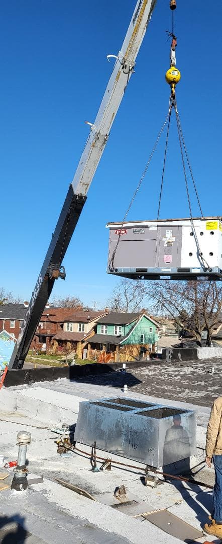 Vertical air conditioner section being hoisted onto a rooftop