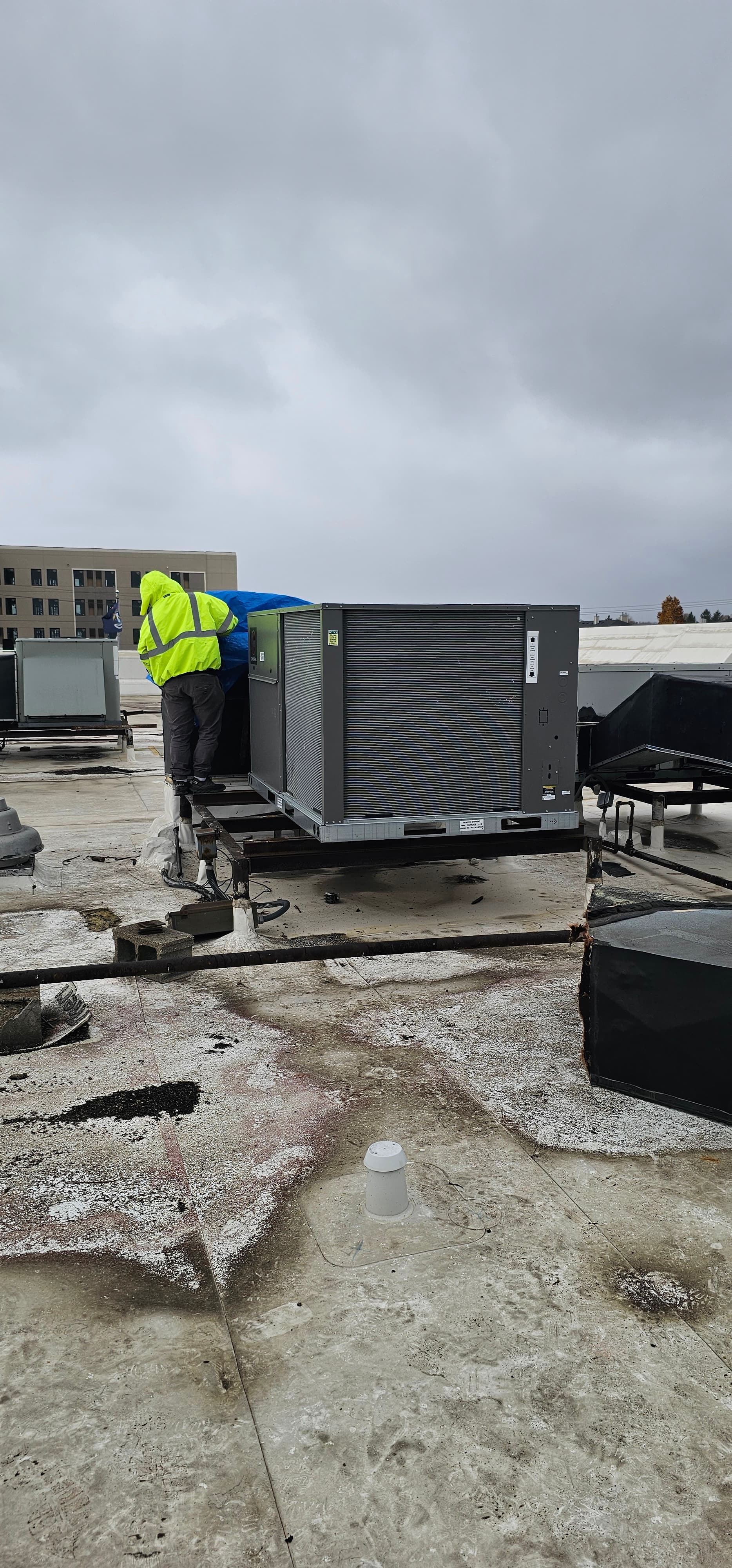 Vertical rooftop unit installation in progress with crew guidance